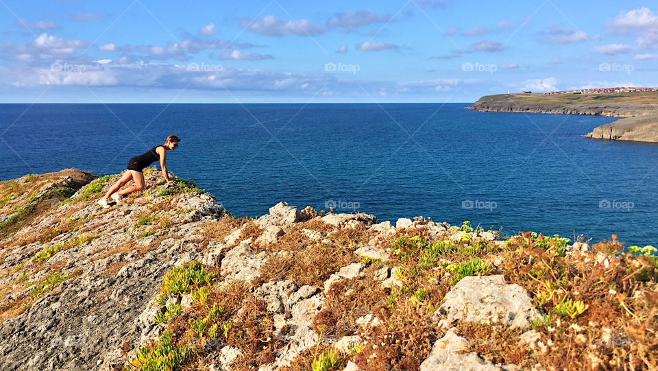 A woman contemplating the ocean on top of the cliff at Cantabria coast, Spain 