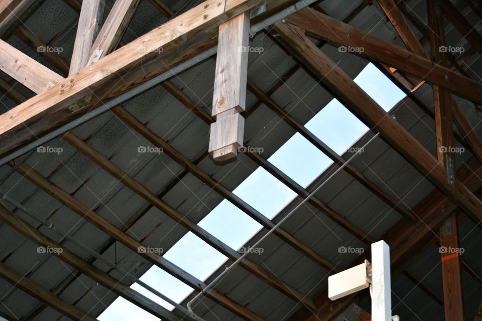 Low angle view of roof structure with missing piece showing a view of the clear blue sky