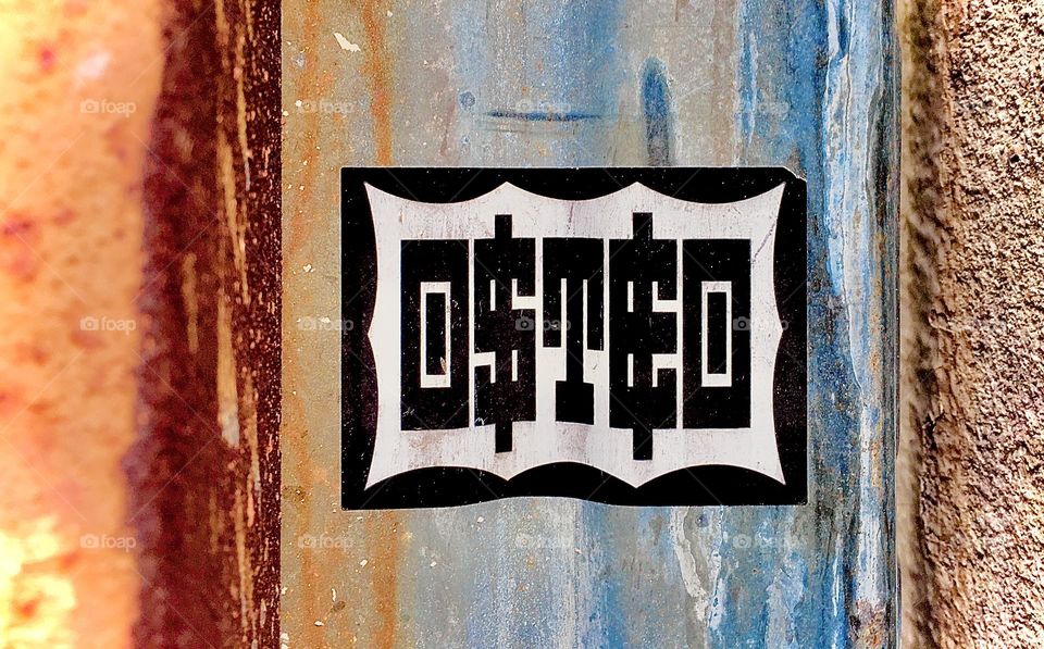A sticker with the inscription „OSTEO“ is glued onto a rippled metallic surface. The colors and shapes make an attractive composition together and the letters seem to subconsciously spell out the message: „Oh, stay!!!“. 2020. Hypnotic Productions