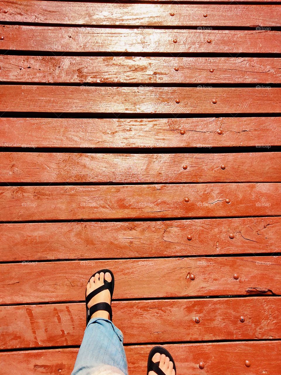 My feet are stepping on the wooden bridge.