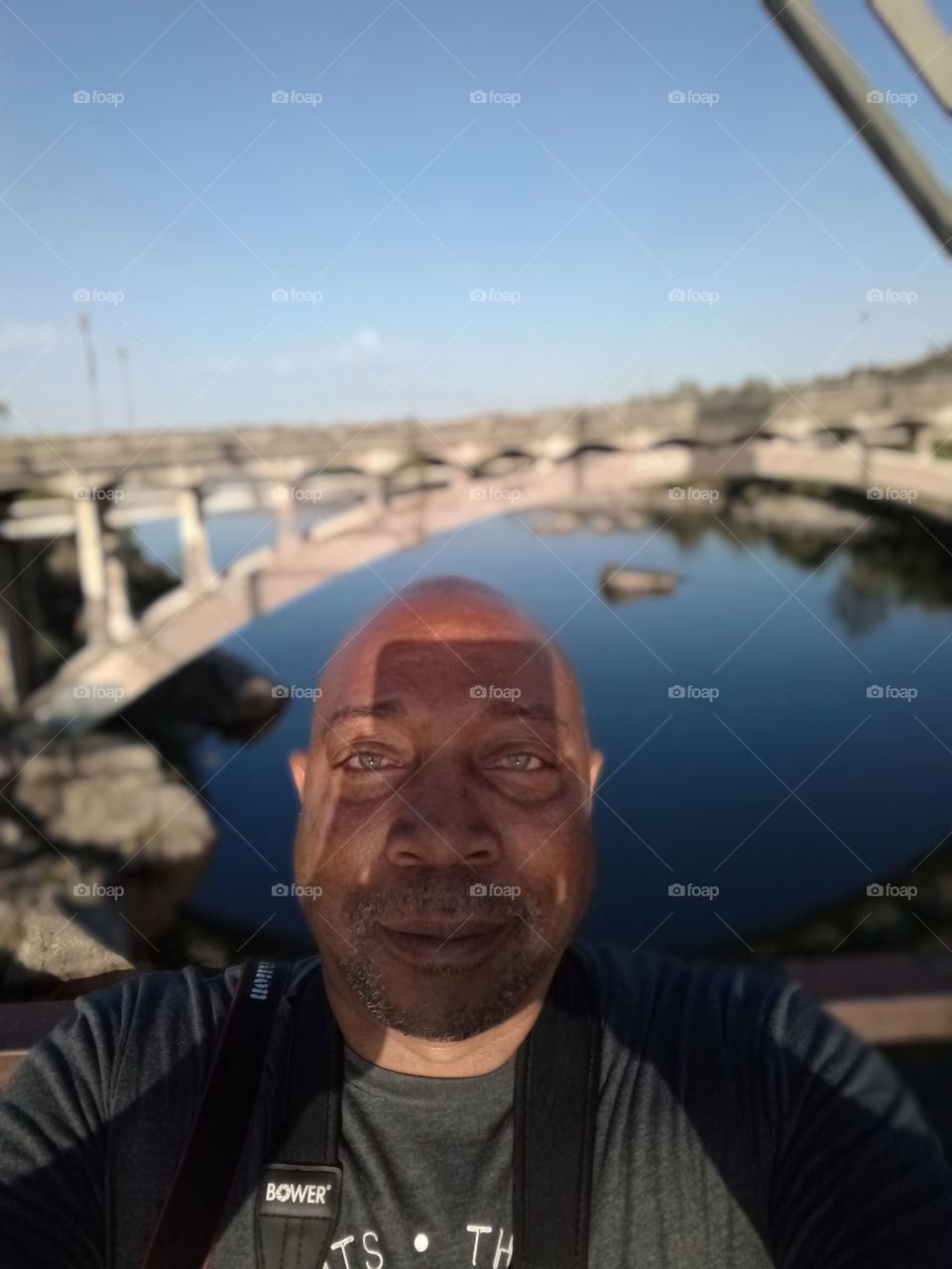 Shadow selfie, with blue Waters and a bridge in the background.