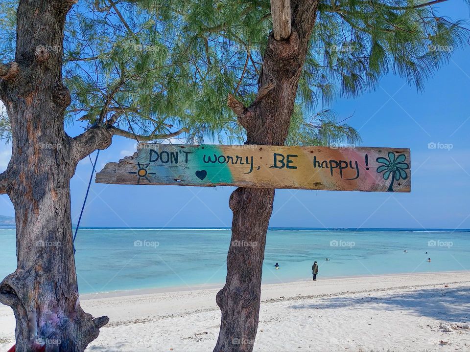 sign With 'don't worry be Happy ' on tropical beach in front of clear water