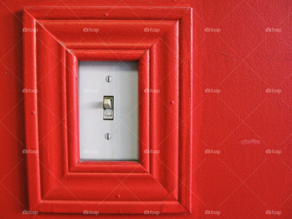 A light switch on a bright red wall