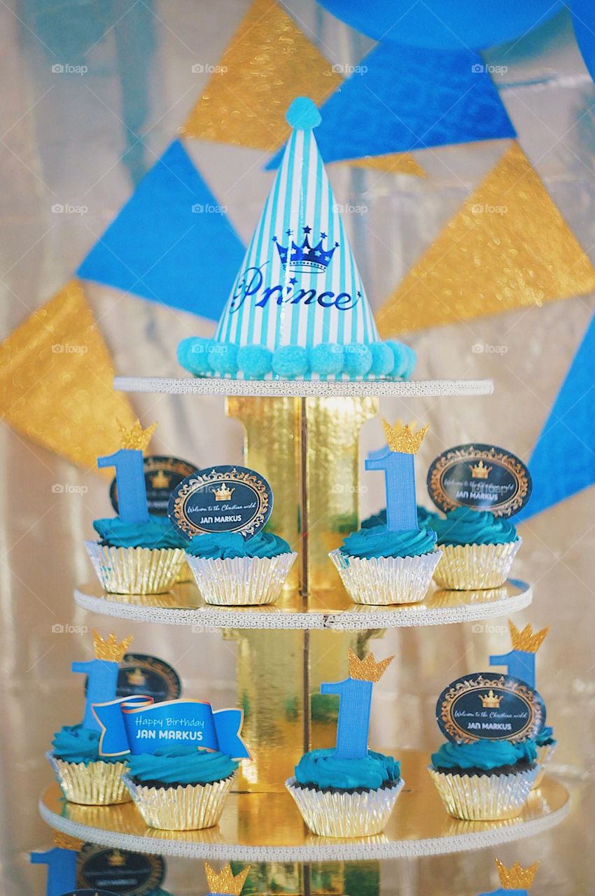 Chocolate cupcakes with blue frosting served for a baby boy’s first birthday party.