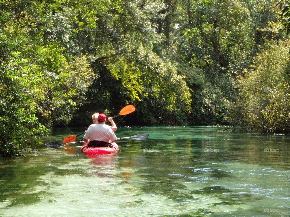 Mom and dad serenely kayaking downstream on a Florida river.
