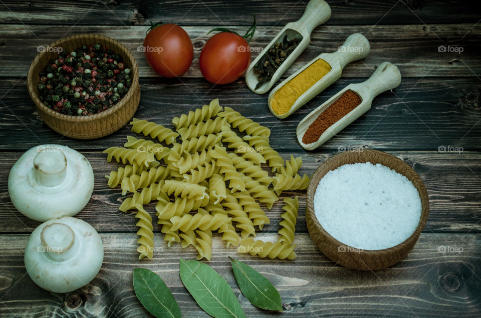 Raw pasta with ingredients and wooden accessories