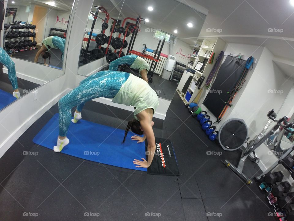 Girl doing yoga in a small studio space with mirrors. 