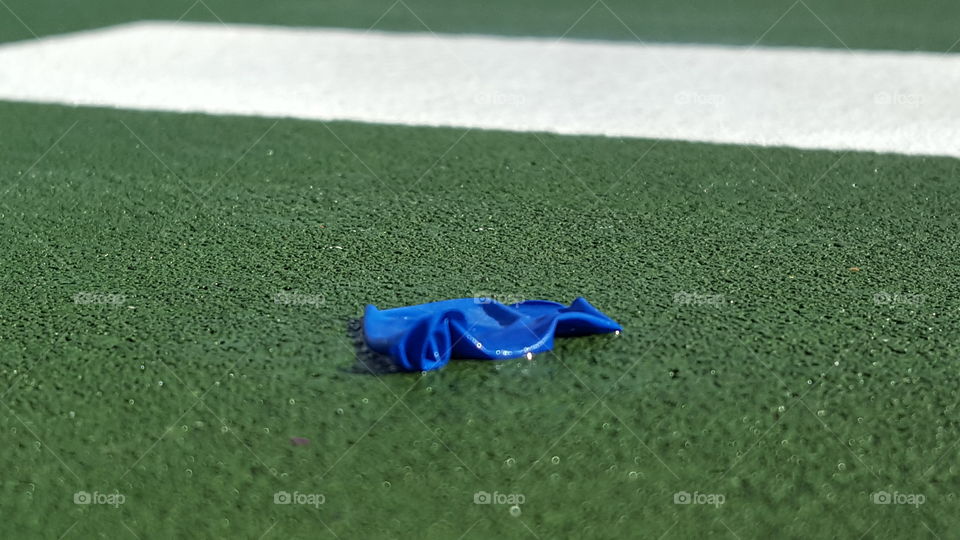 Close up of popped water balloon on marching band practice field after summer band camp water fight