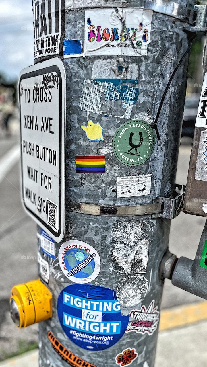 Pole at traffic light with Pride flag sticker on it, Pride colors in everyday life, colors of Pride in the city, colorful stickers on traffic signal poles, crossing the street 