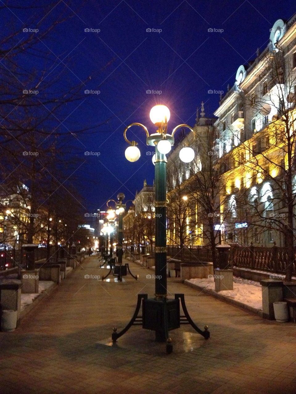 Lit lamppost on boulevard at night