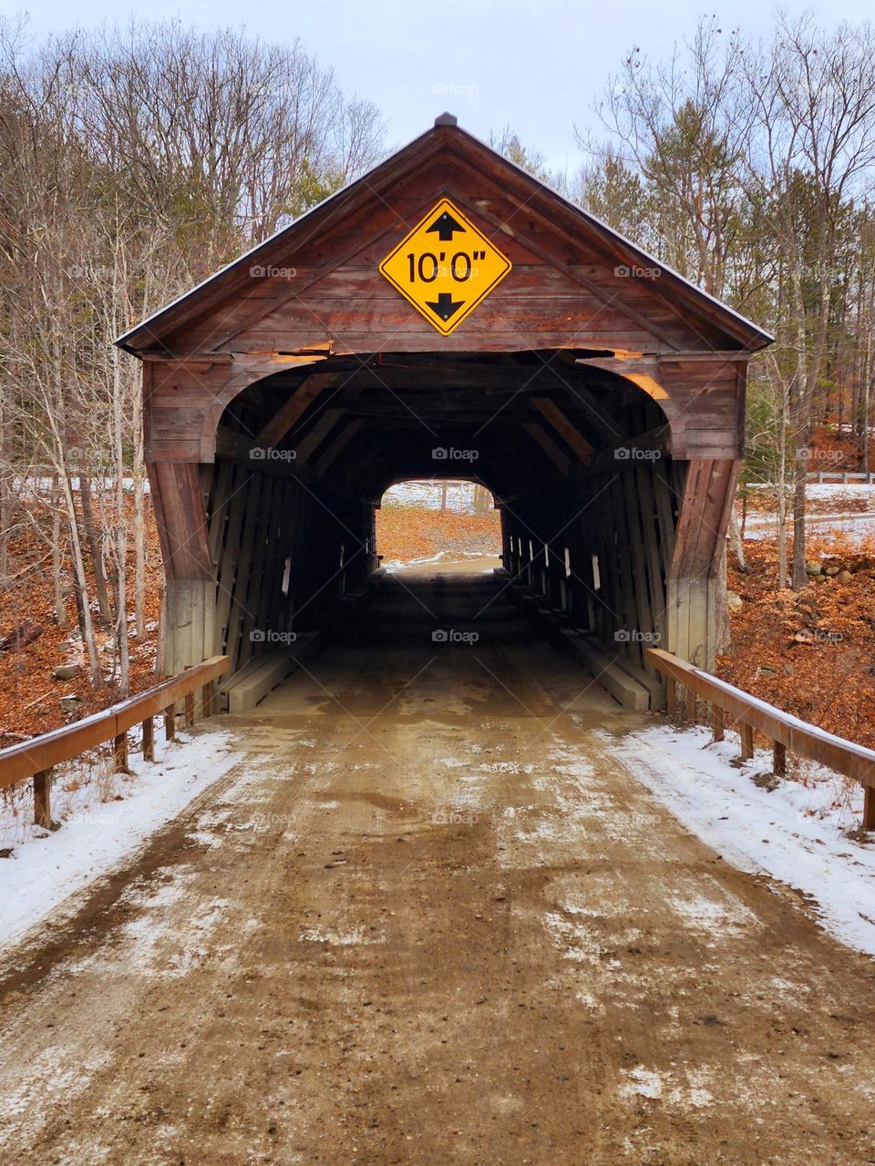 A covered bridge in New England shows signs of wear and tear and a unfortunate experience with a high vehicle