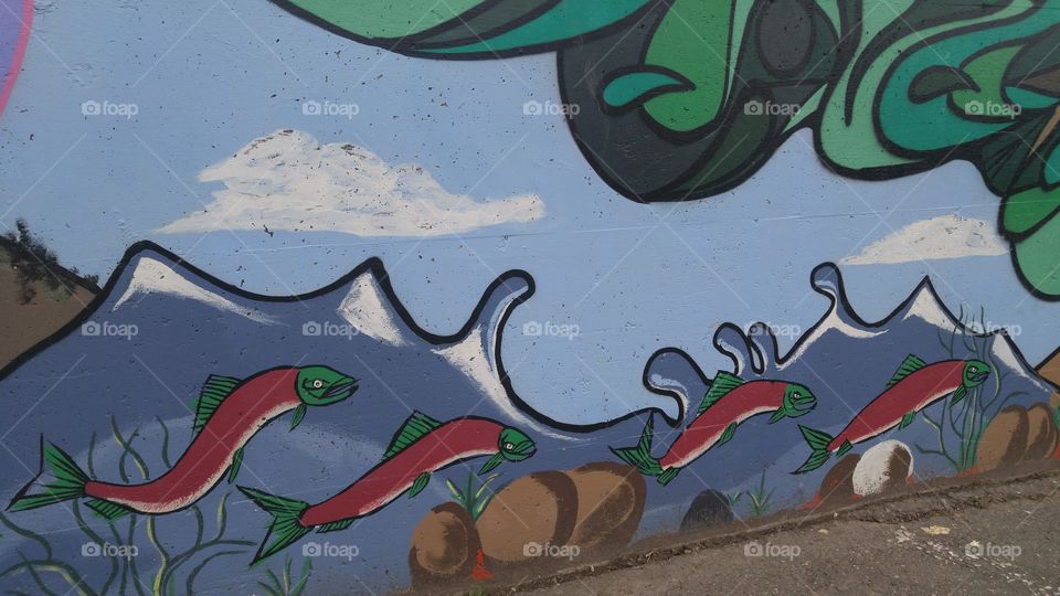 Parking lot wall mural of sockeye salmon spawning in river.