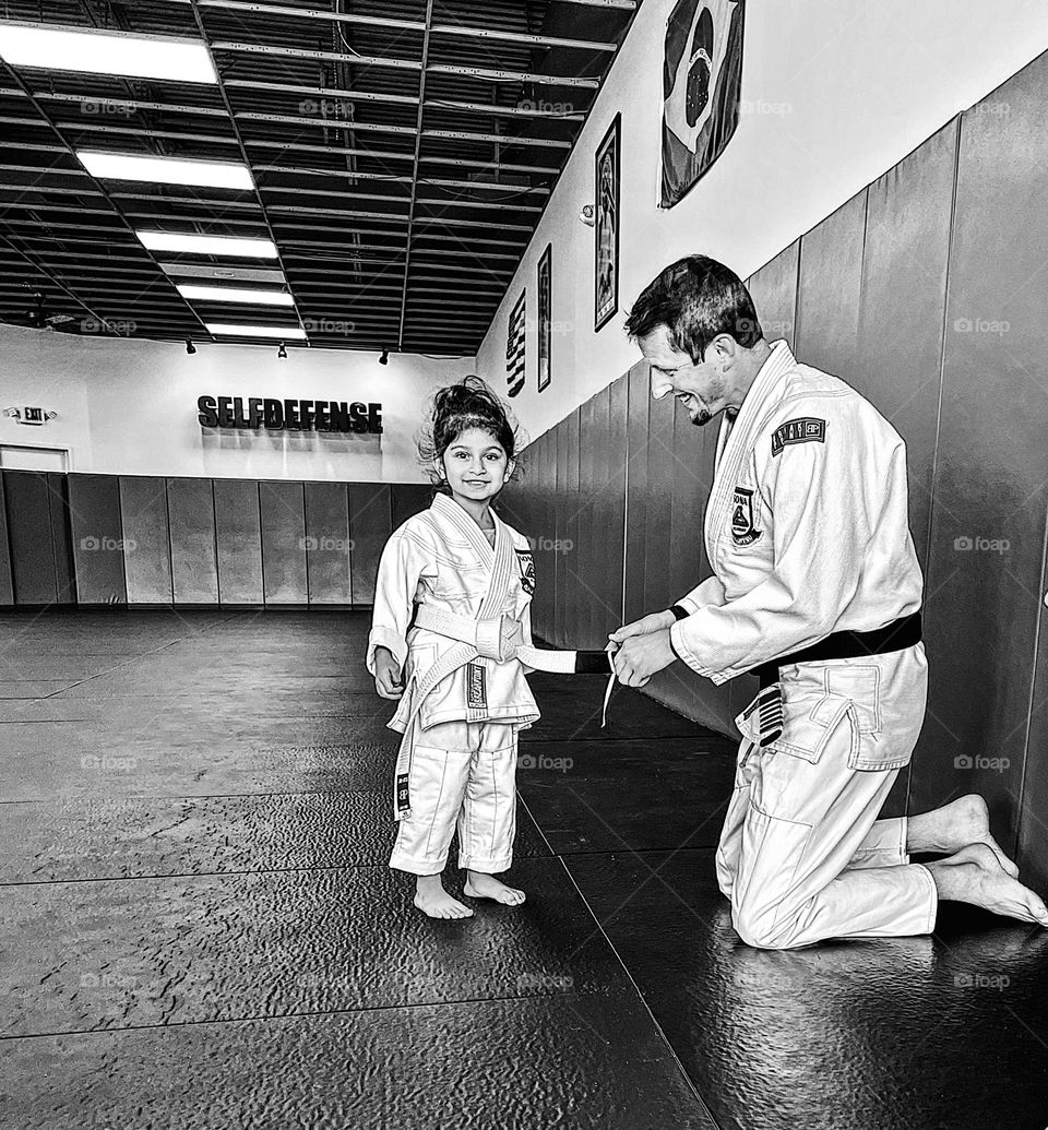 Little girl in Jiu Jitsu class, little girl gets her first stripe in Jiu Jitsu class, excited little girl gets promotion in class, becoming a martial arts expert 