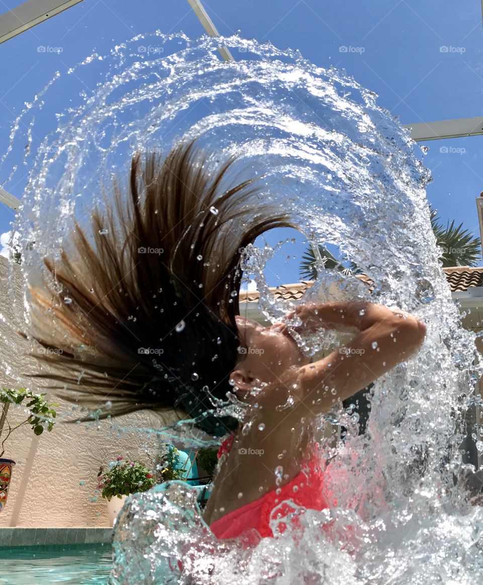 Crystal clear water arch created by a teenager throwing her head and long hair backwards 