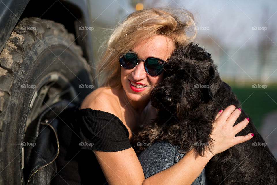 Cute blond girl near car with her black dog