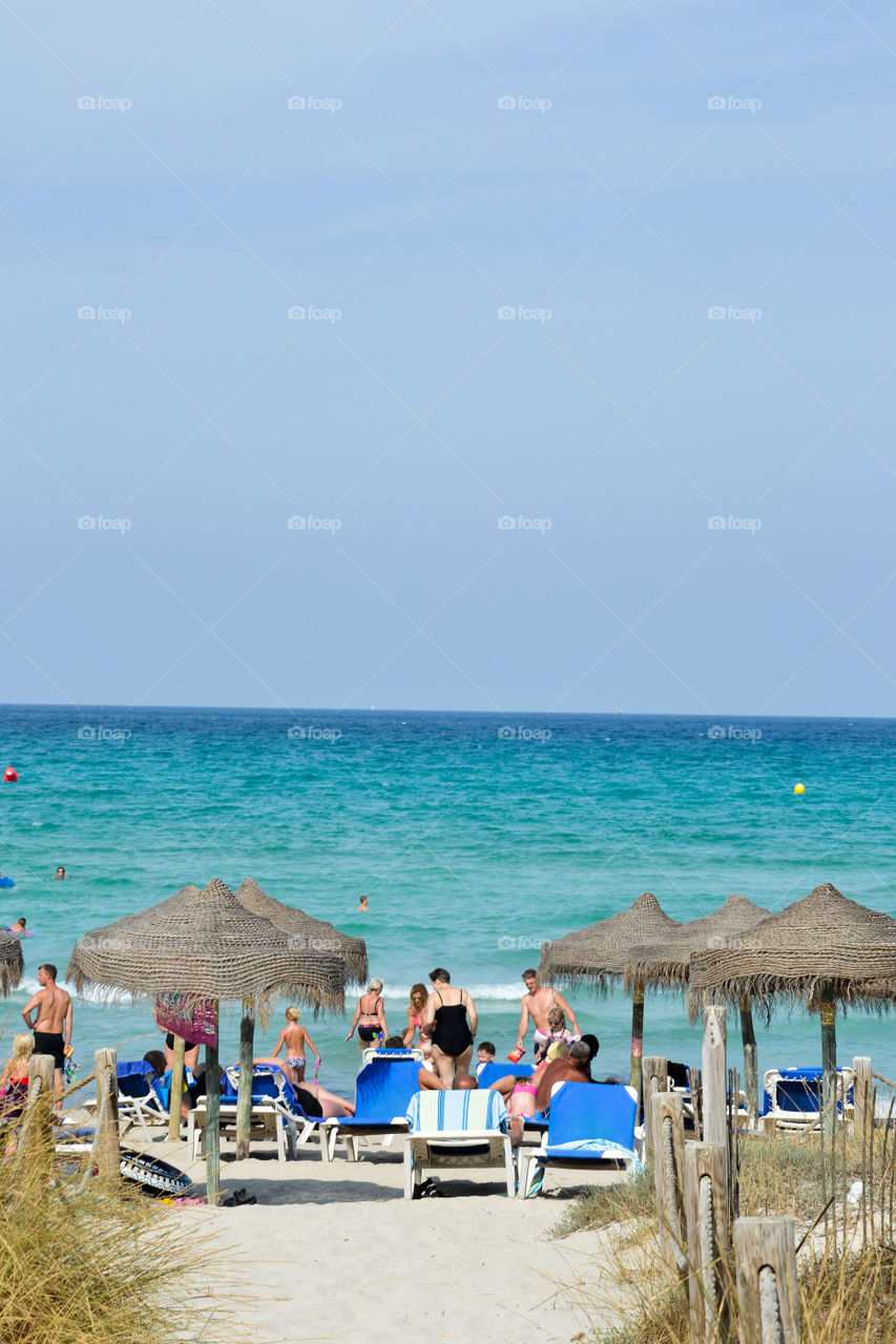 Tourists enjoying the beach at Alcudia Pins Majorca Spain.