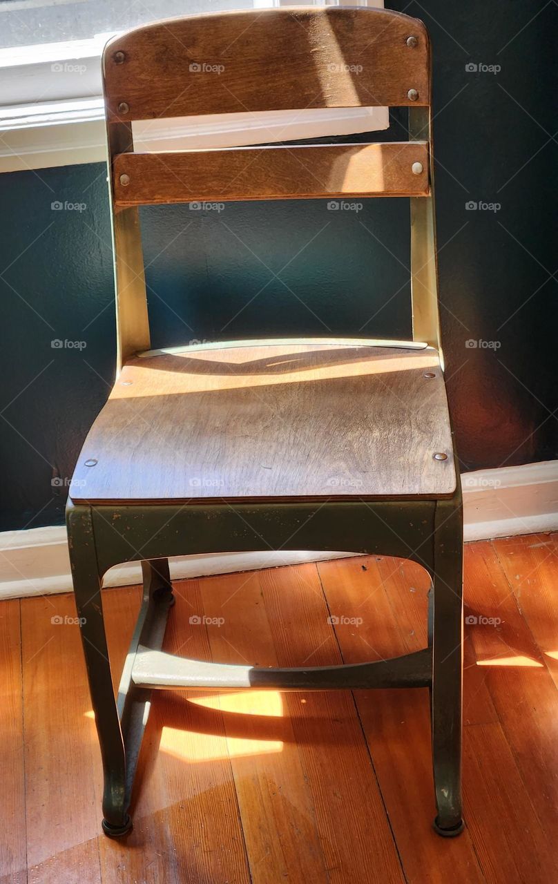 light shining through the window on an old-fashioned school chair