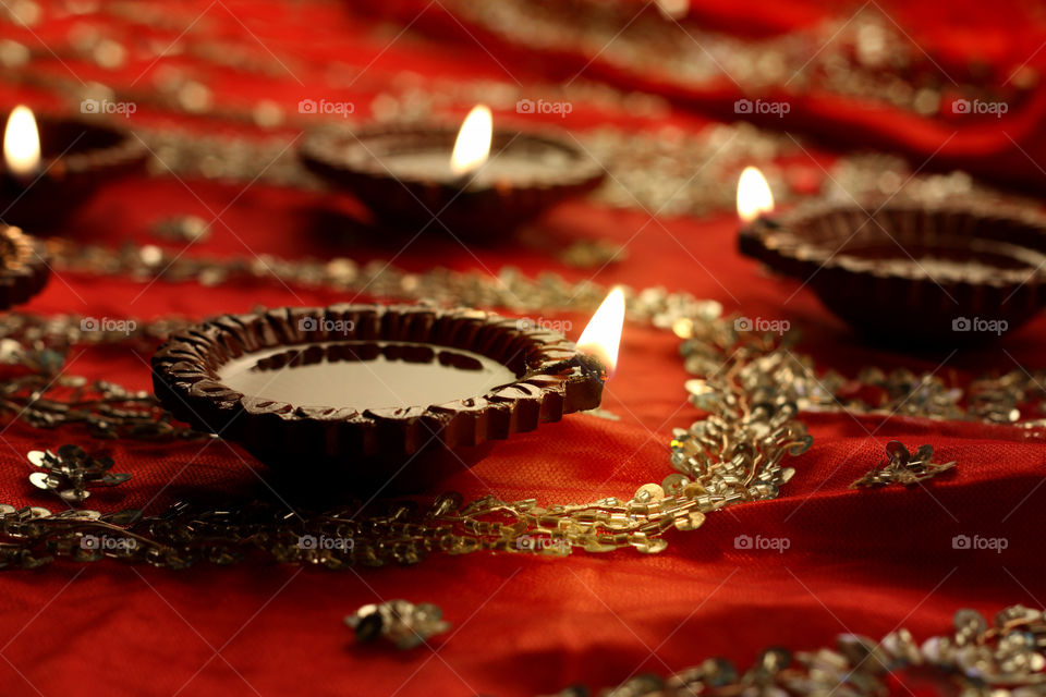 Beautiful Diwali diya oil lamp on red with bokeh blur
