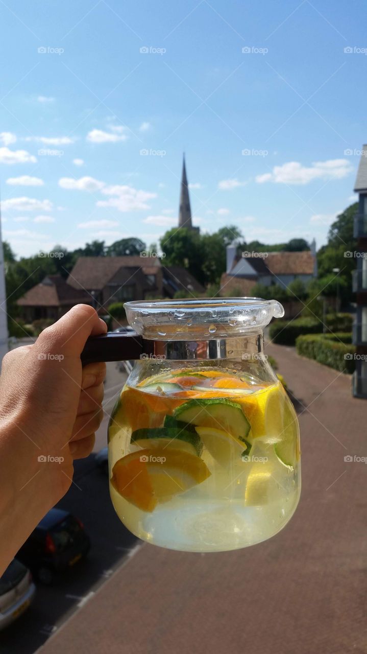 water in a glass jar tea pot is infused with lemon orange fruit and cucumber vegetable ideal for a hot summer day
