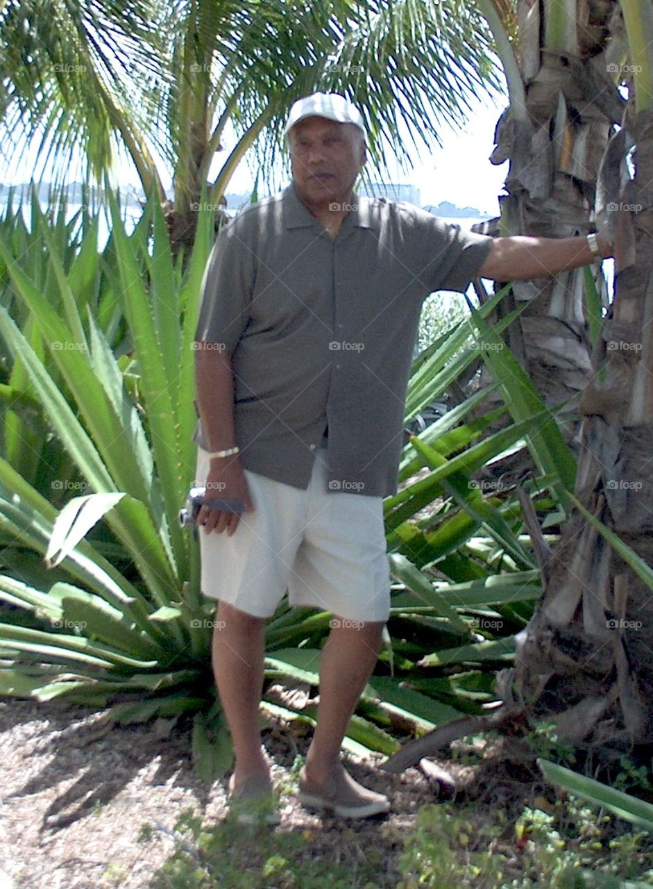 Man holding camera standing alone at botanical garden 