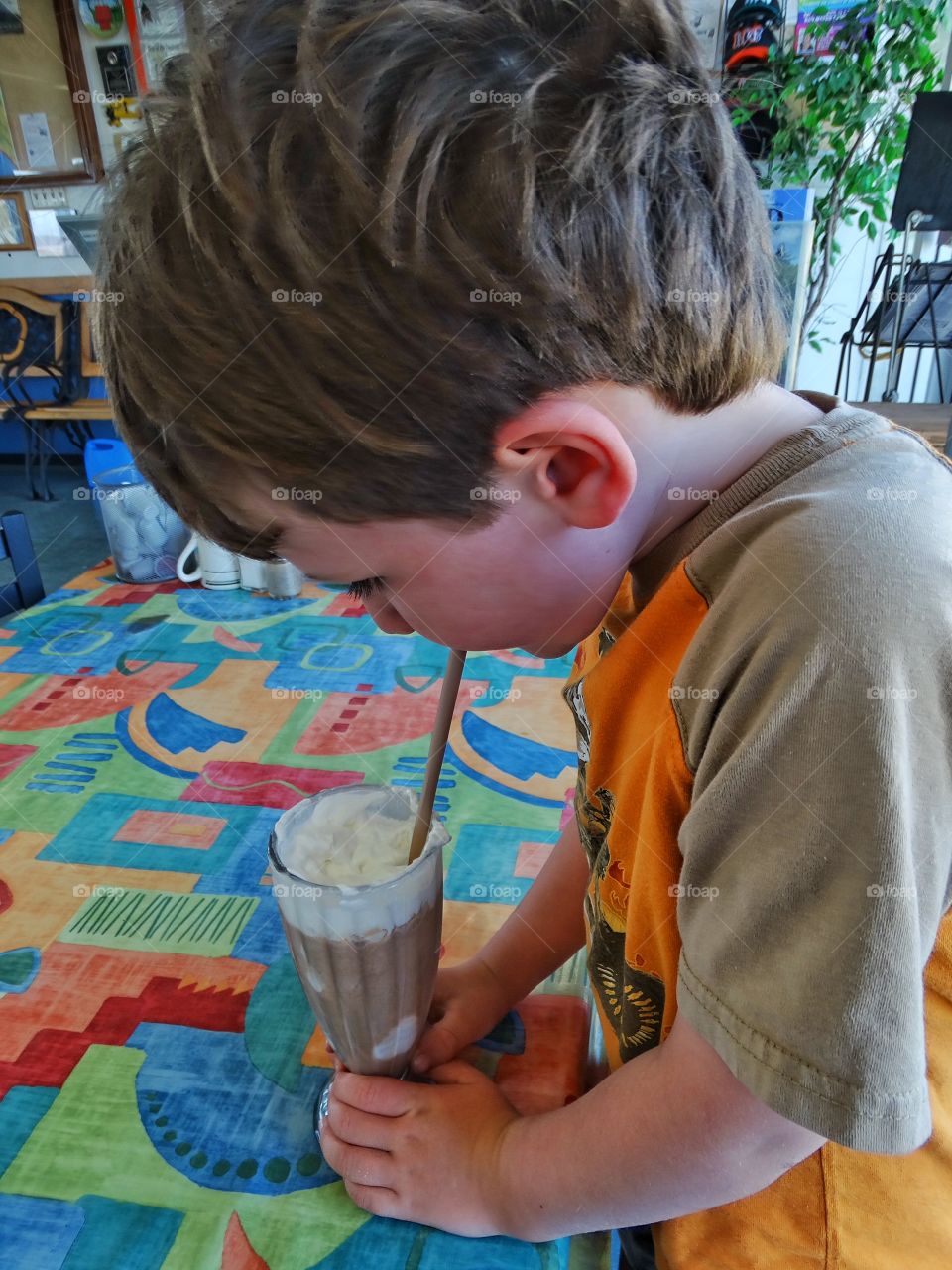 Chocolate Milkshake. Young Boy Enjoying A Chocolate Milkshake At An American Diner
