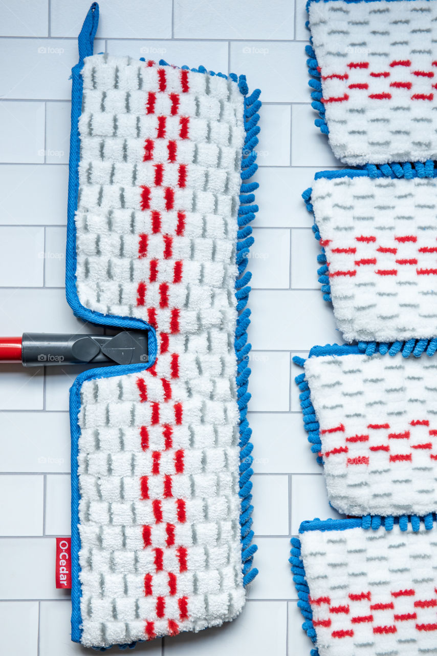 Flat lay of an O-Cedar mop and microfiber mop head refills on a tile floor