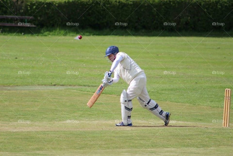 Cricketer in white uniform playing in Mid Wales