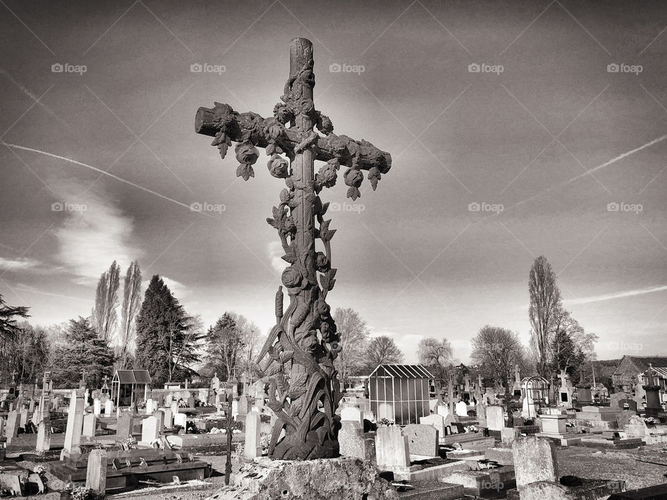 Black and white image of a prominent cross in a cemetery, Gueret, France 