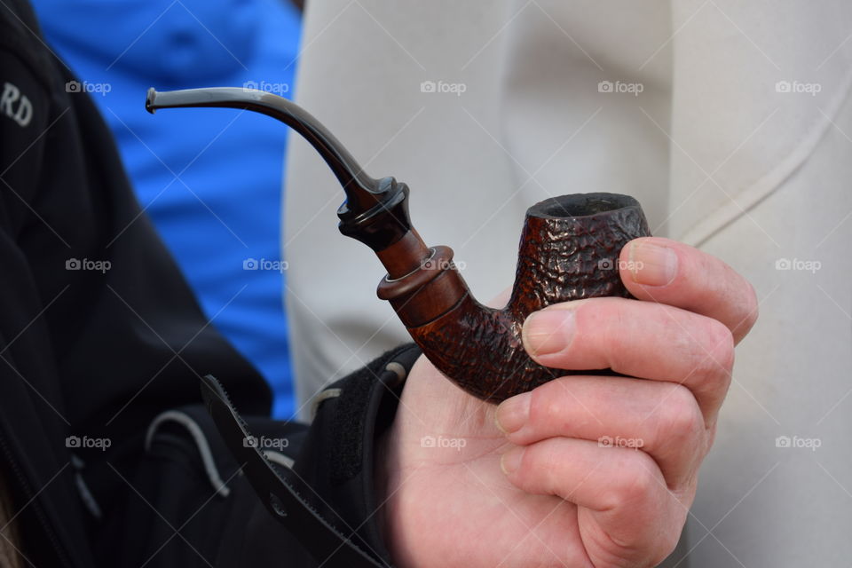 An elderly man holding a pipe