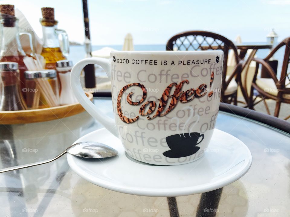 Coffee mug with the logo good coffee is a pleasure on a beach bar table