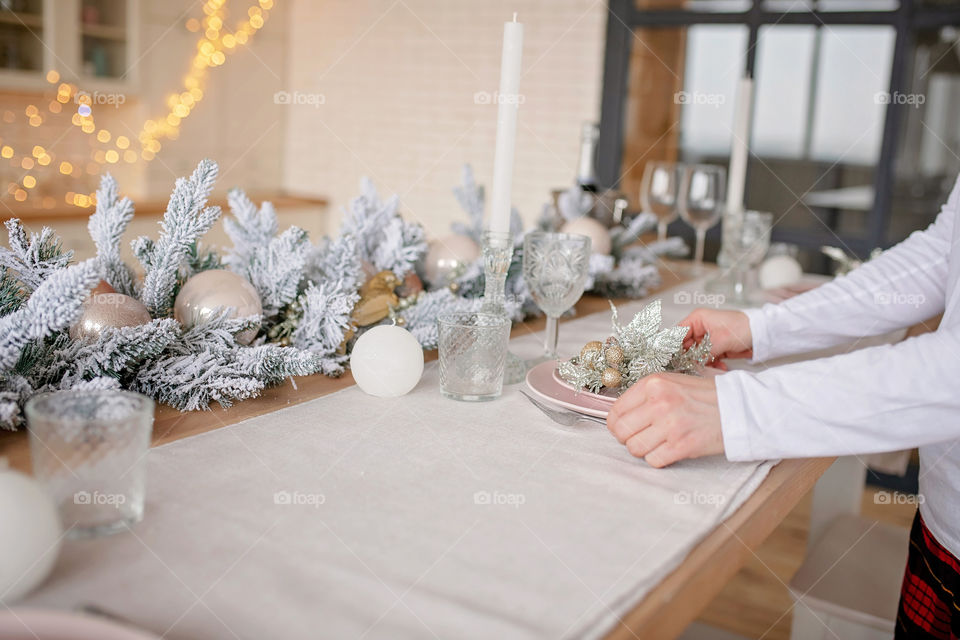 man sets a beautiful decorated winter table for a festive dinner.  Merry Christmas and Happy New Year.