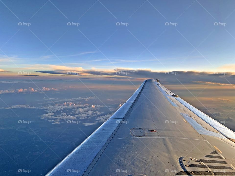 Flying high above the clouds as the sky changes colors from the sunrise 