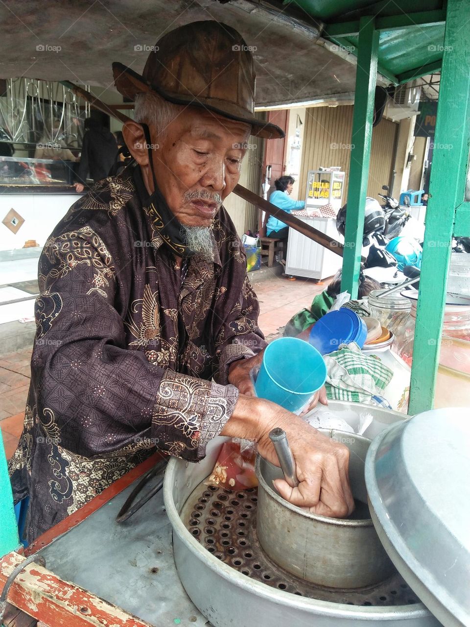 A father sells green bean porridge at a traditional Indonesian market.