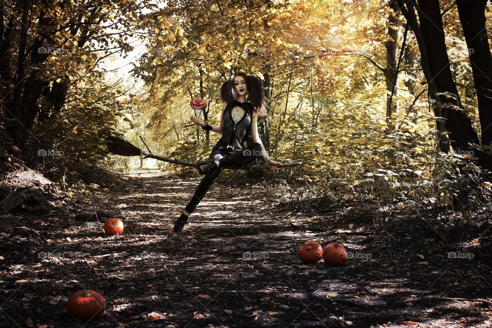 Woman sitting on broom in forest