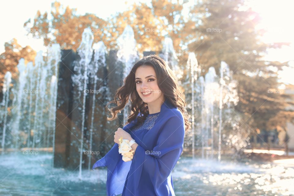 Woman standing against fountain smiling