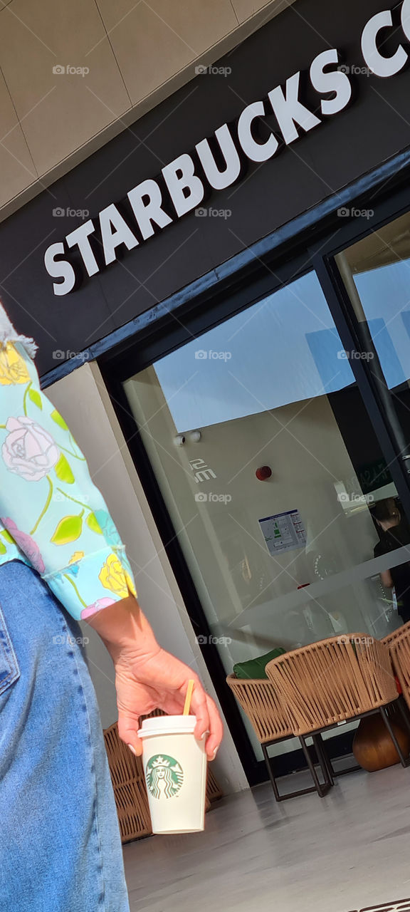 Holding starbucks coffee cup in front of store