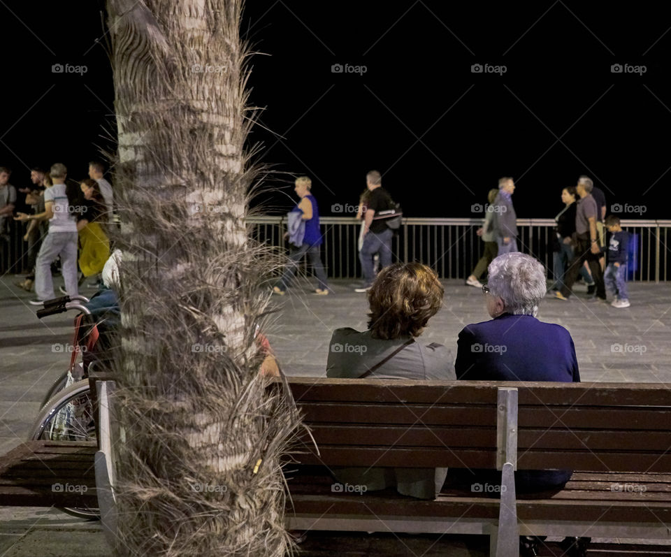 Elderly women sitting in a street bench at night