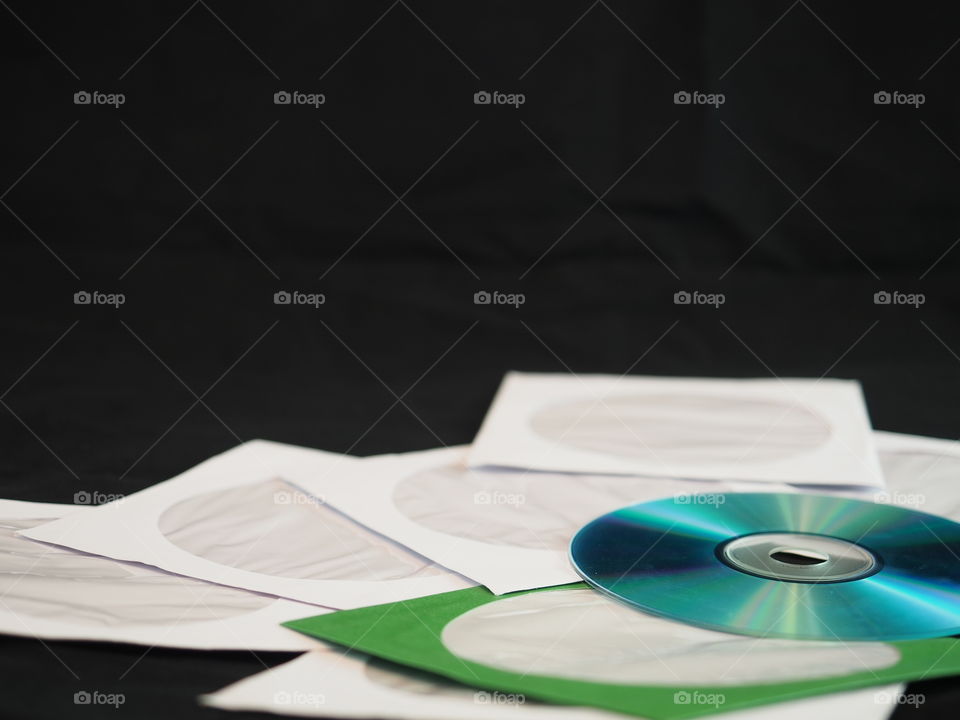 Several white paper CD Sleeves are offset by a green sleeve with a CD on the side and a black background. 