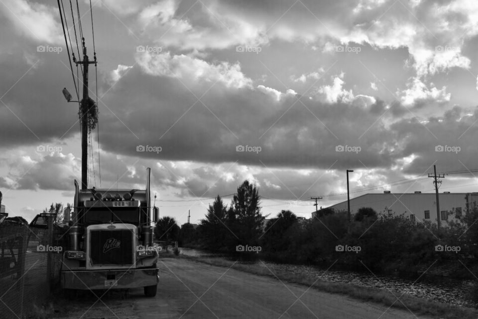 A black and white photo of a truck next to a junkyard showing the pollution and industrial side of cities