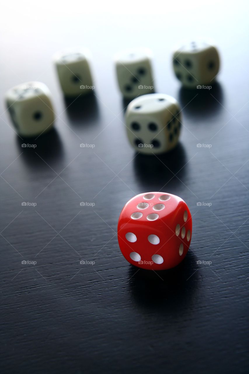 red and white game dice. 1 red game dice in front of 5 white game dice