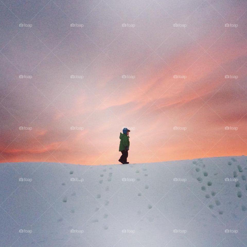 Boy walking on big pile of snow