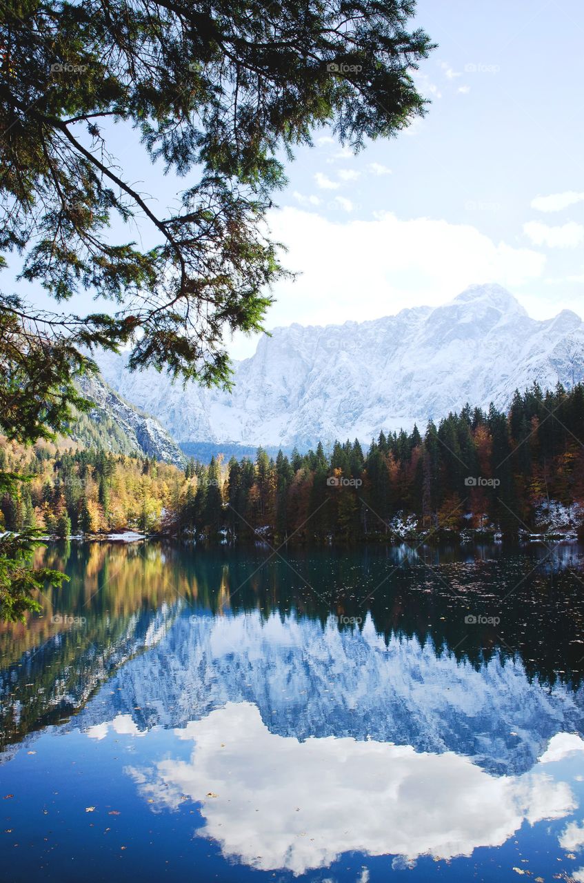 Scenic view of the autumn mountains landscape and colorful forest reflected in the lake, Laghi di Fusine Italy.