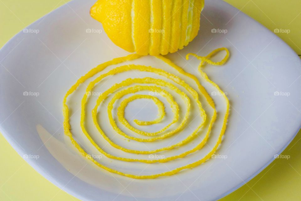 Fruits! - Lemon and spiraled lemon peel on a white plate with yellow background  