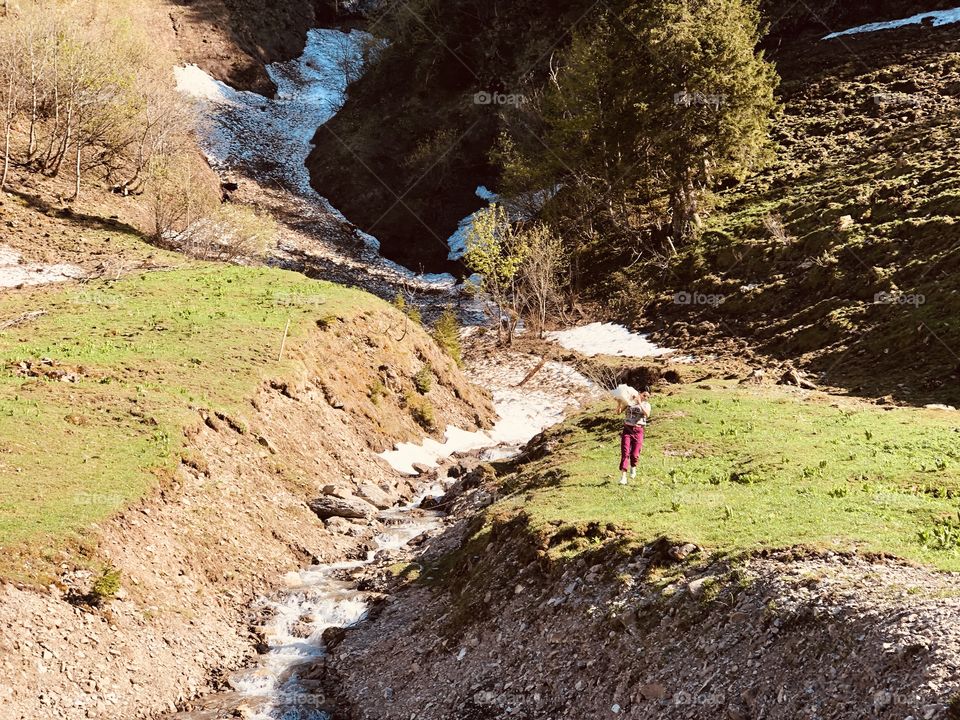 water flows, stream, waterfall, snow in the mountains, laughter, snow in hands, snow in holes, green grass, spring