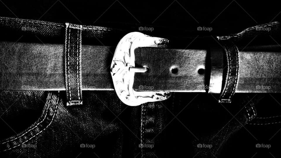 Vestimenta. Calça jeans, presilhas, costuras, bolsos... com cinto de couro com fivela inox. Imagem em preto e branco/Silhouette.
