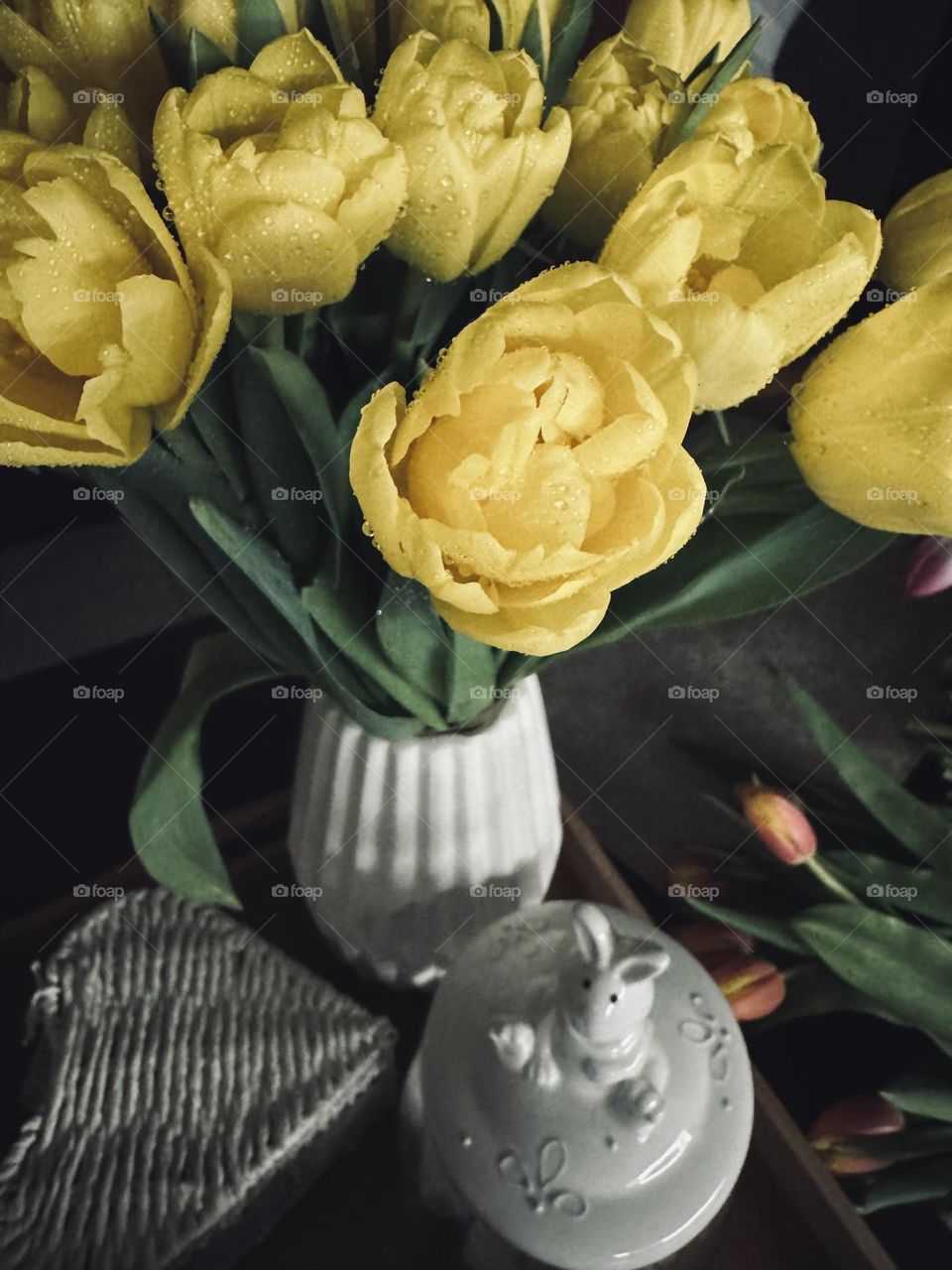 Yellow bouquet of tulips in a white vase stand on the kitchen table. Kitchen interior background 