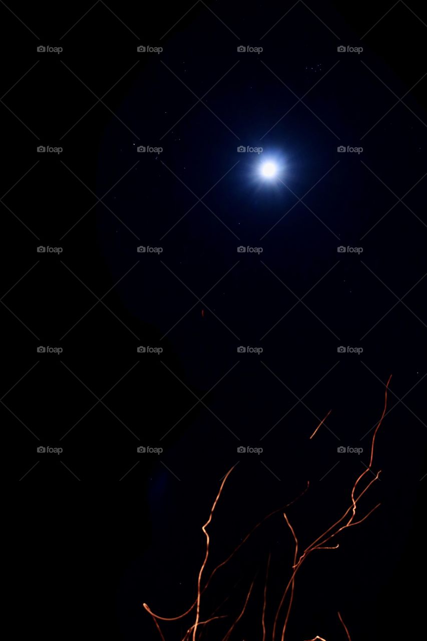 A full moon at night sitting by a campfire.