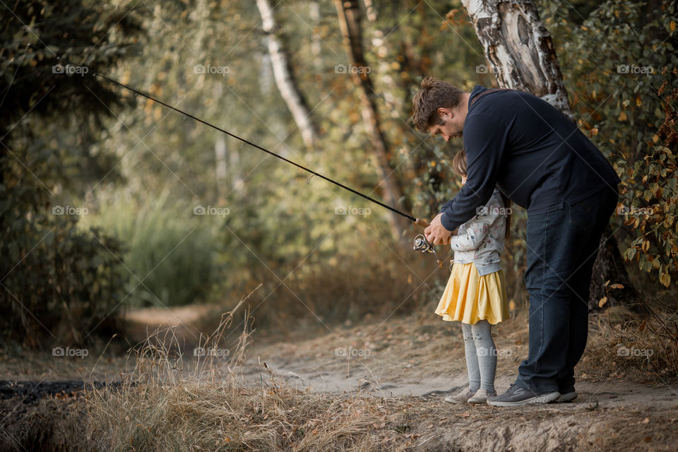 Family fishing on a lake at autumn day 