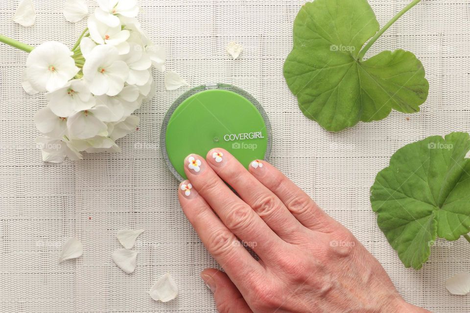 Woman's hand with beautiful manicure holding case with make up powder