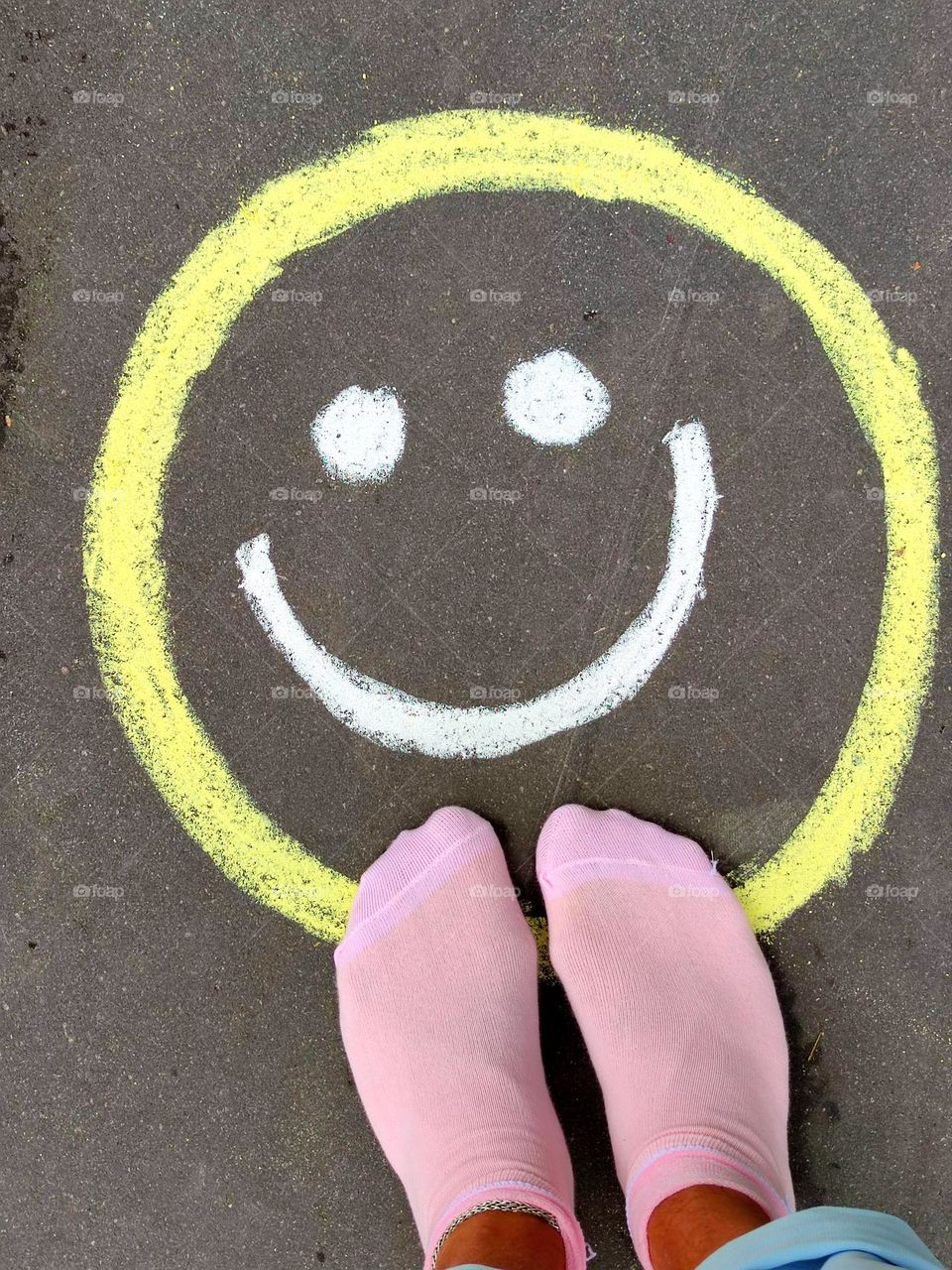 Happiness.  A happy smiley face is drawn in chalk on the pavement, which smiles.  Photo from which the beholder has a smile on his face and happy emotions